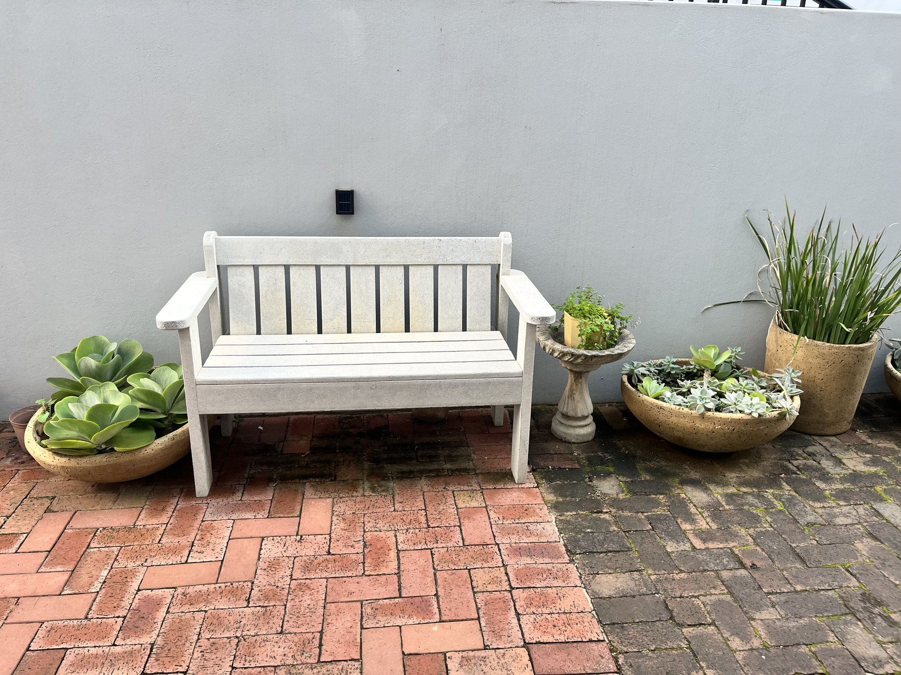 Garden bench and potted plants inside 4Shore Guesthouse